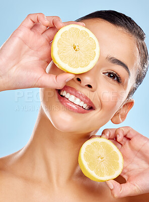 Buy stock photo Studio portrait of an attractive young woman posing with lemon against a blue background