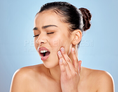 Buy stock photo Studio shot of an attractive young woman experiencing toothache against a blue background