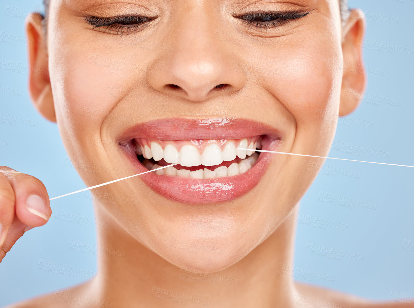 Buy stock photo Studio shot of an attractive young woman flossing her teeth against a blue background