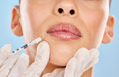 Buy stock photo Woman, mouth and needle in hand for plastic surgery with anti aging results and medical process in studio. Female client, cosmetic change and closeup injection with filler for lips by blue background