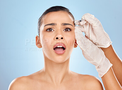 Buy stock photo Studio portrait of an attractive young woman looking anxious while receiving a botox injection against a blue background