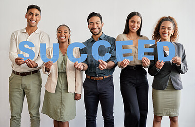Buy stock photo Shot of a group of young businesspeople holding letters that spell out the word ‘succeed’