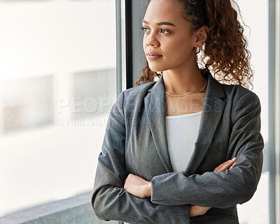 Buy stock photo Shot of a young businesswoman gazing out of a window thoughtfully in a modern office