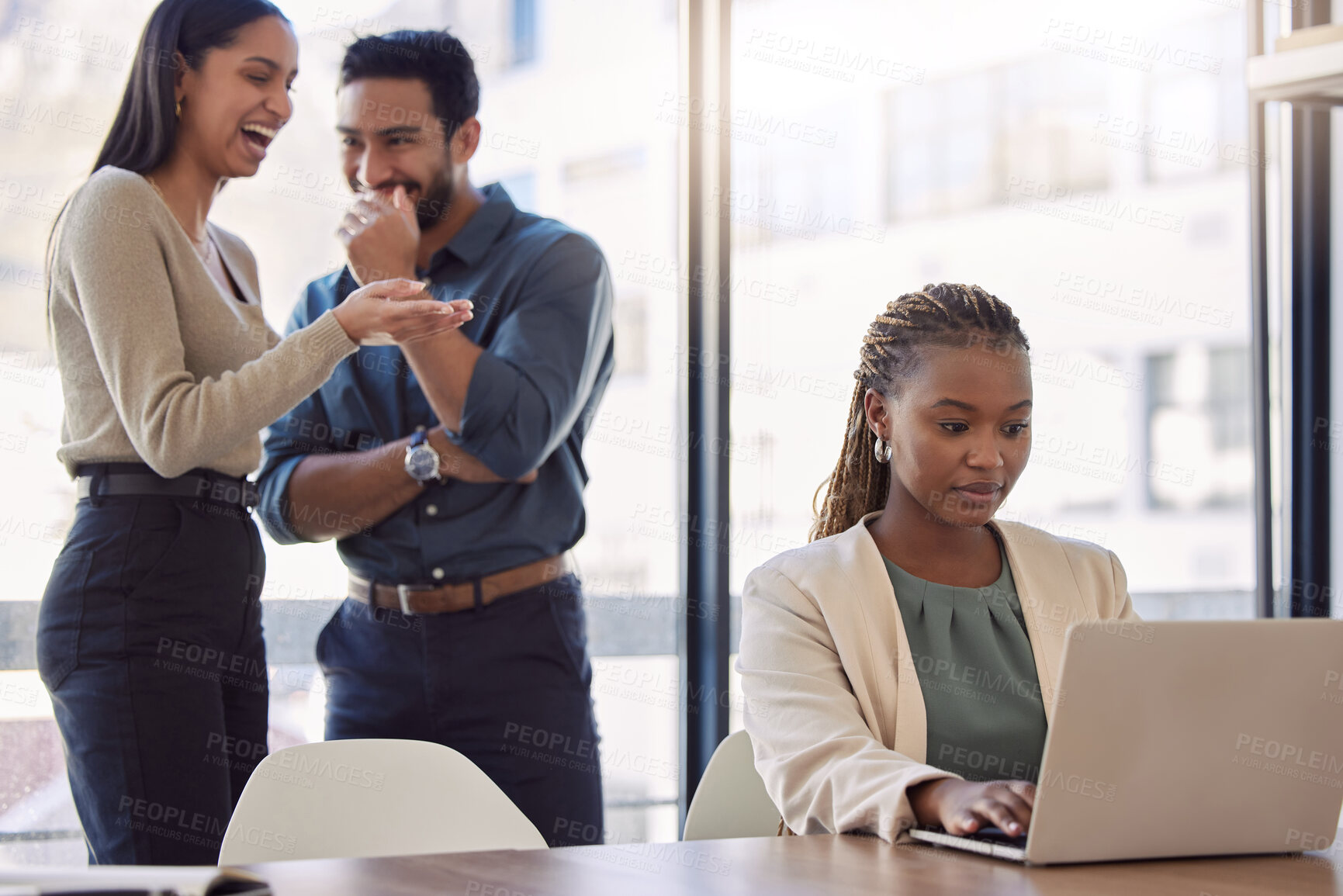 Buy stock photo Office bully, woman and working at laptop with coworkers laughing in a corporate workplace about gossip. Young black person typing on a computer with internet and joke with staff being mean at desk