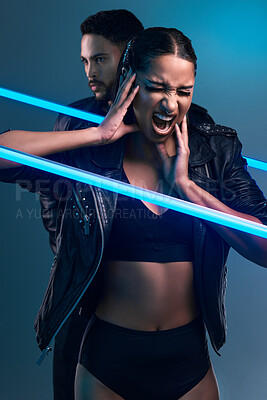 Buy stock photo Conceptual shot of a stylish young man and woman posing in studio against a blue background