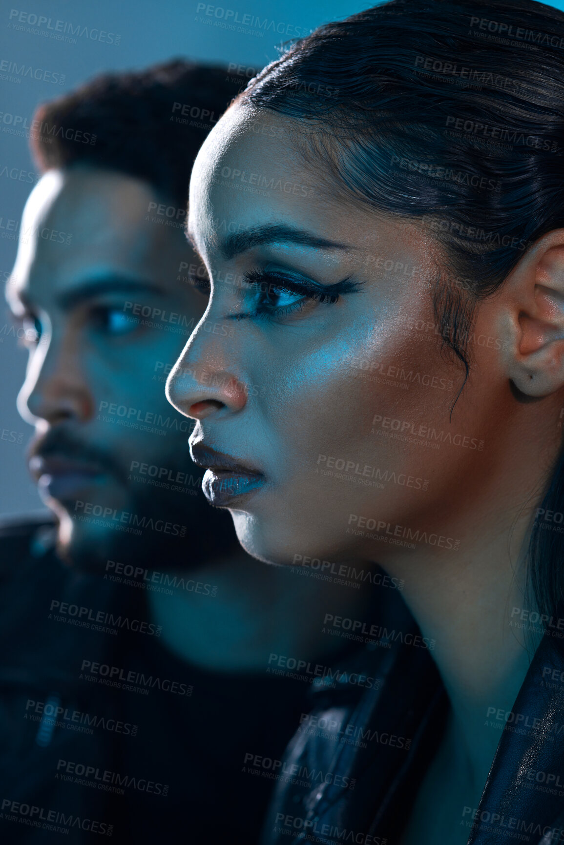 Buy stock photo Conceptual shot of a stylish young man and woman posing in studio against a blue background