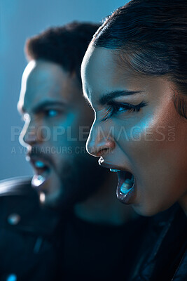 Buy stock photo Conceptual shot of a stylish young man and woman posing in studio against a blue background