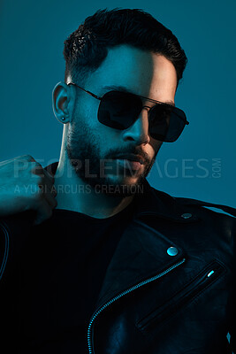 Buy stock photo Conceptual shot of a stylish young man posing in studio against a blue background