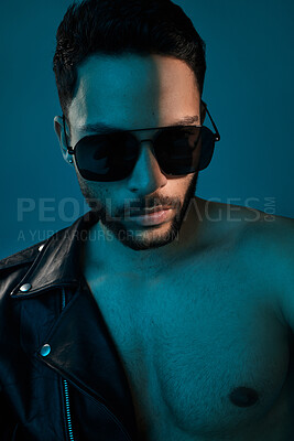 Buy stock photo Conceptual shot of a stylish young man posing in studio against a blue background