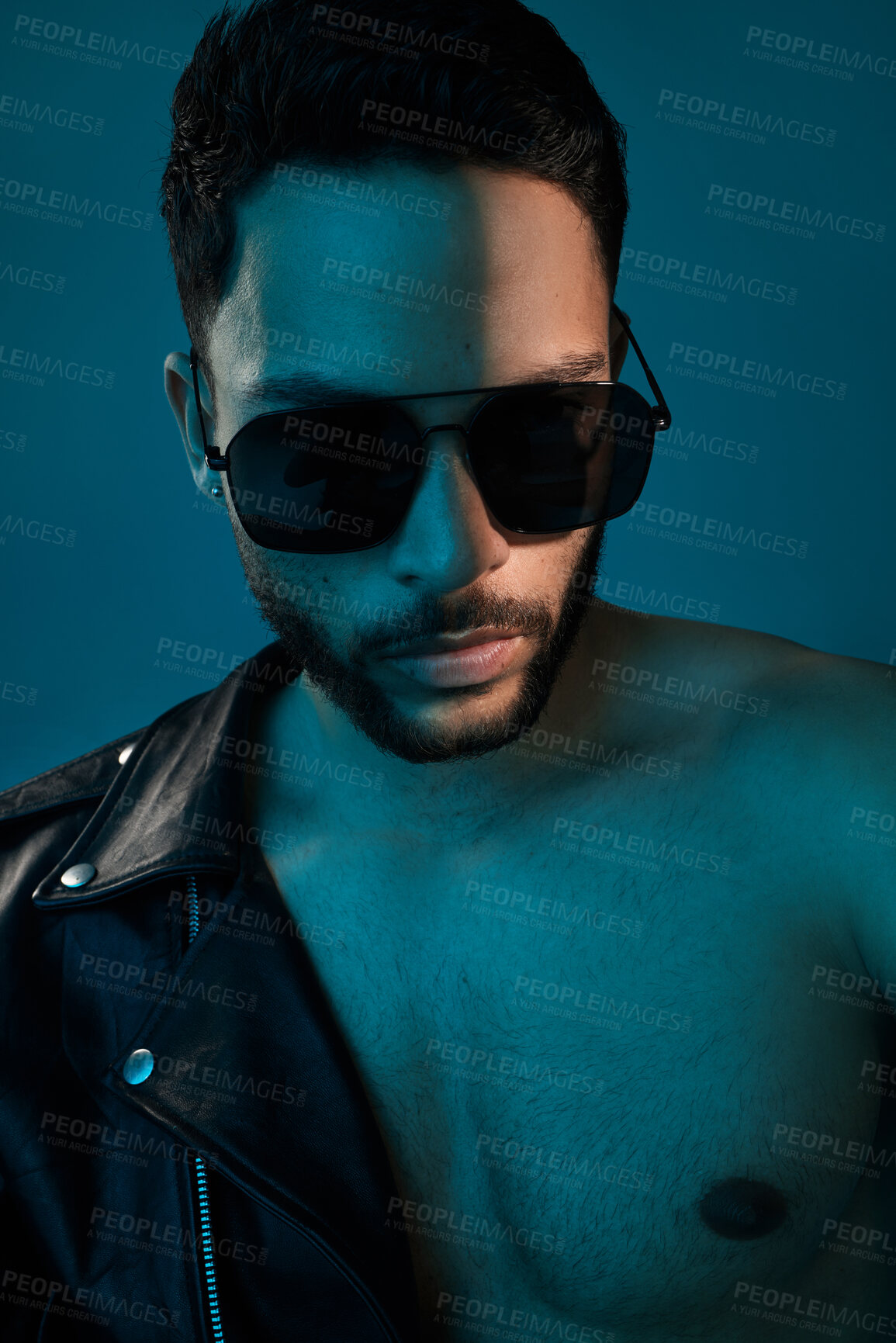 Buy stock photo Conceptual shot of a stylish young man posing in studio against a blue background