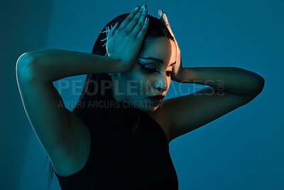 Buy stock photo Conceptual shot of a stylish young woman posing in studio against a blue background