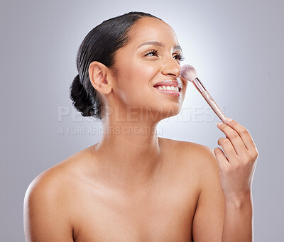 Buy stock photo Shot of an attractive young woman standing alone in the studio and feeling playful while holding a makeup brush