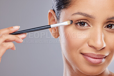 Buy stock photo Shot of an attractive young woman standing alone in the studio and applying eyeshadow