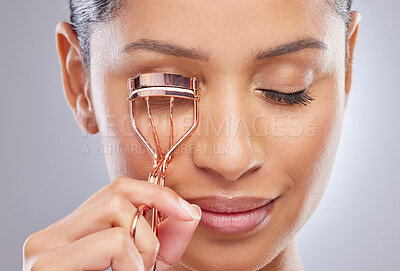 Buy stock photo Eyelash curler, face and woman in studio for makeup, cosmetic and application on grey background. Lashes, curling and Indian female model with metal tool for volume, glamour or beauty aesthetic