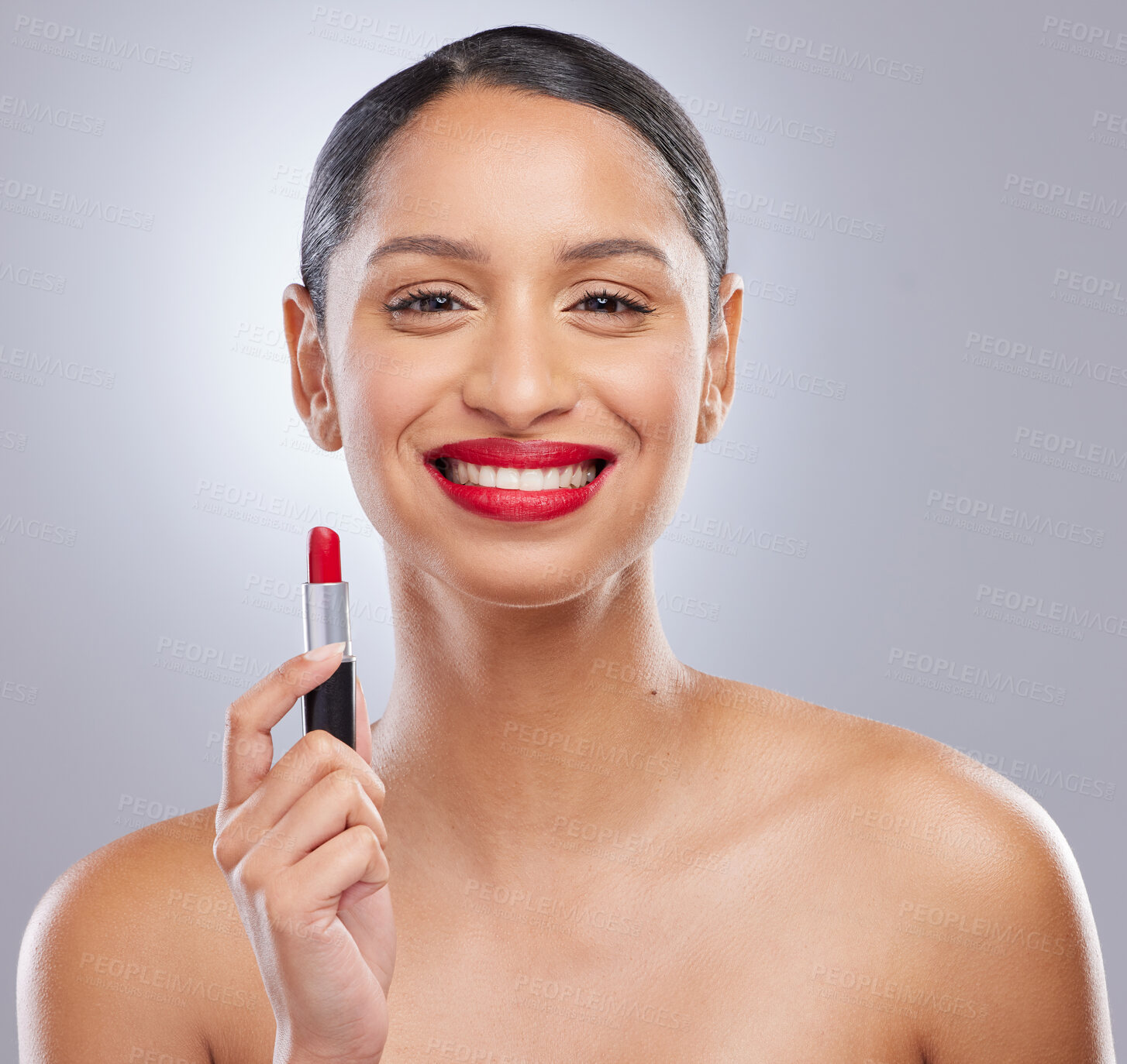 Buy stock photo Shot of an attractive young woman standing alone in the studio and posing while holding red lipstick