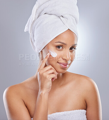 Buy stock photo Shot of an attractive young woman applying moisturiser to her skin in the studio