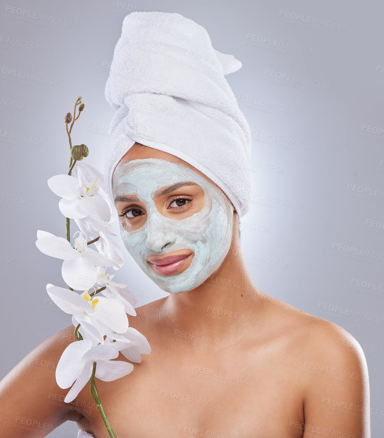 Buy stock photo Shot of an attractive young woman wearing a face mask and holding an orchid in the studio