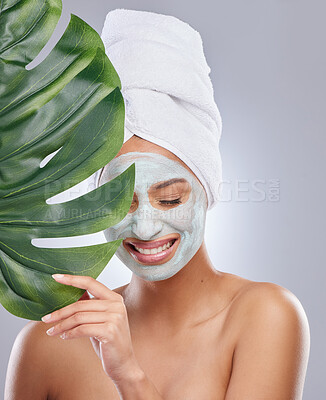 Buy stock photo Shot of an attractive young woman wearing a face mask and holding a monstera leaf in the studio