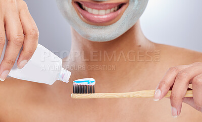 Buy stock photo Cropped shot of an unrecognisable woman wearing a face mask and applying toothpaste to her toothbrush in the studio