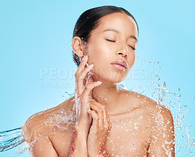 Buy stock photo Skincare, water splash and face of woman on blue background for wellness, healthy skin and cleaning. Bathroom, shower and female person with drop for facial grooming, washing and body care in studio