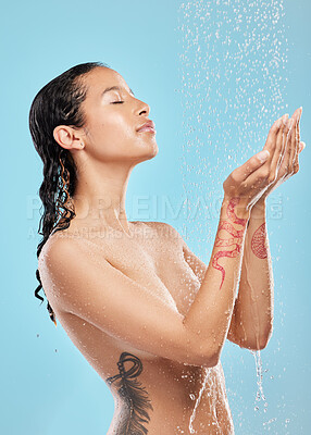 Buy stock photo Shot of a beautiful young woman enjoying a shower against a blue background