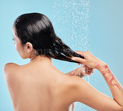 Buy stock photo Shot of a beautiful young woman enjoying a shower against a blue background