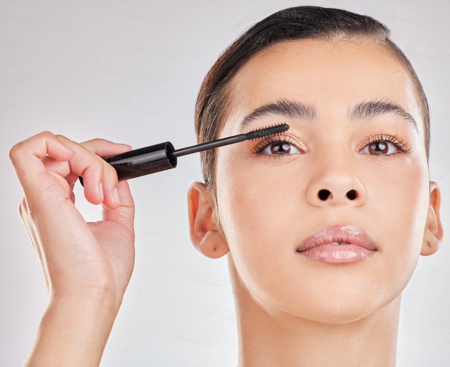 Buy stock photo Shot of a young woman applying makeup to her face against a grey background