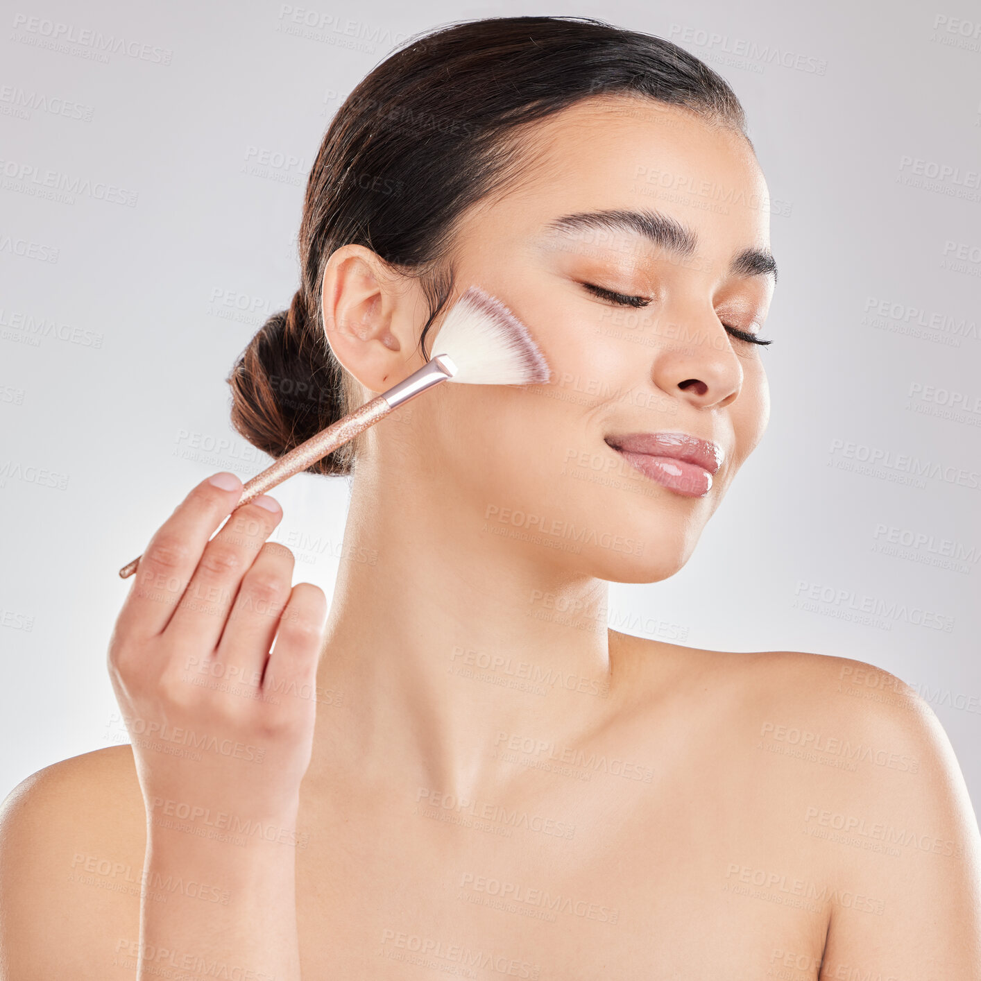 Buy stock photo Shot of a young woman applying makeup to her face against a grey background