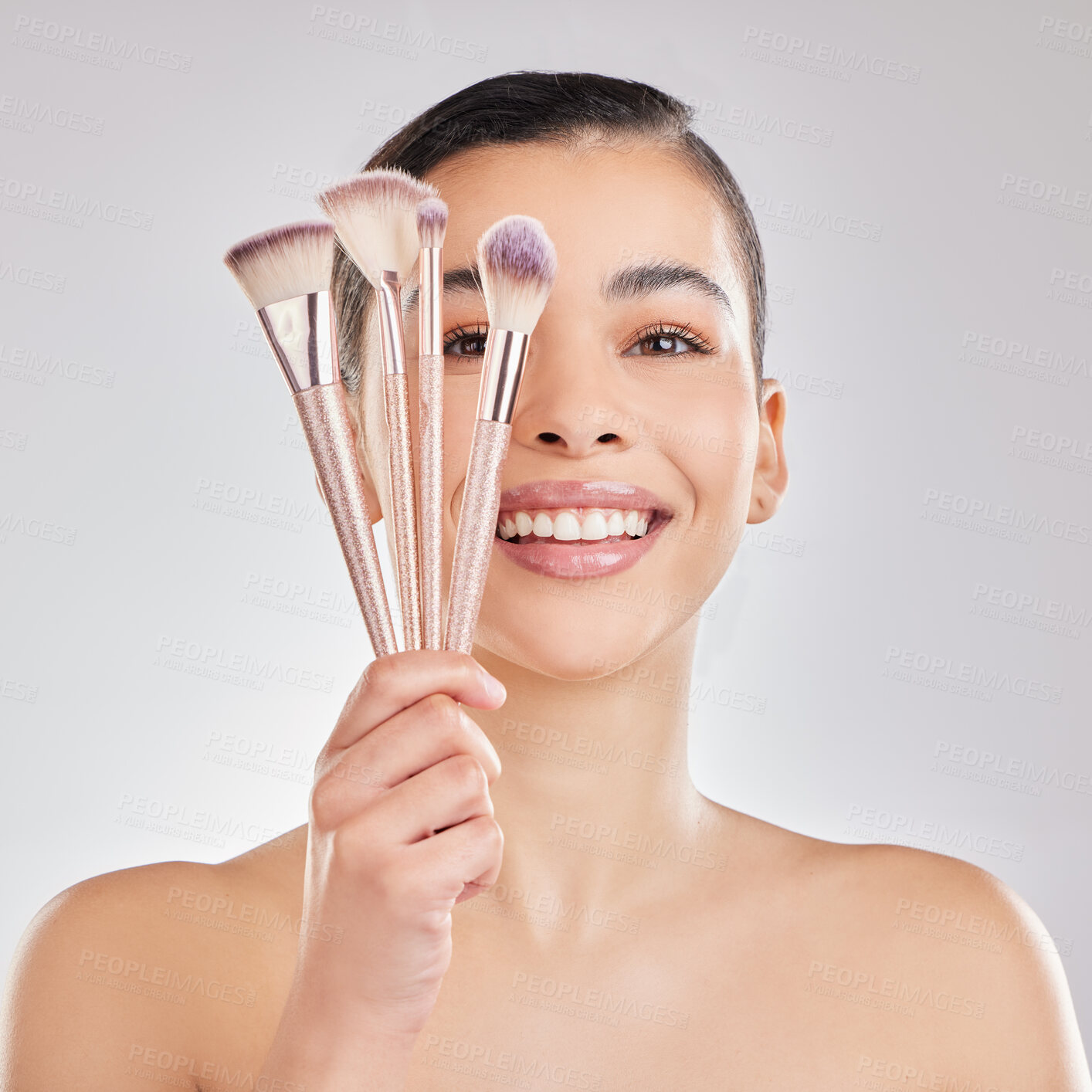 Buy stock photo Shot of a young woman applying makeup to her face against a grey background