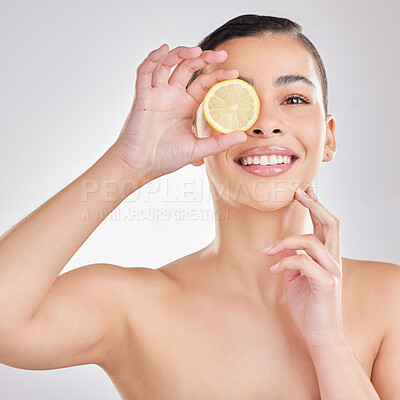 Buy stock photo Studio portrait of a young woman posing with half a lemon against a grey background