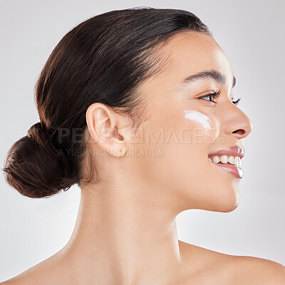 Buy stock photo Shot of a young woman applying a cream to her face against a grey background