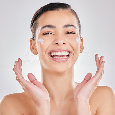 Buy stock photo Shot of a young woman applying a cream to her face against a grey background