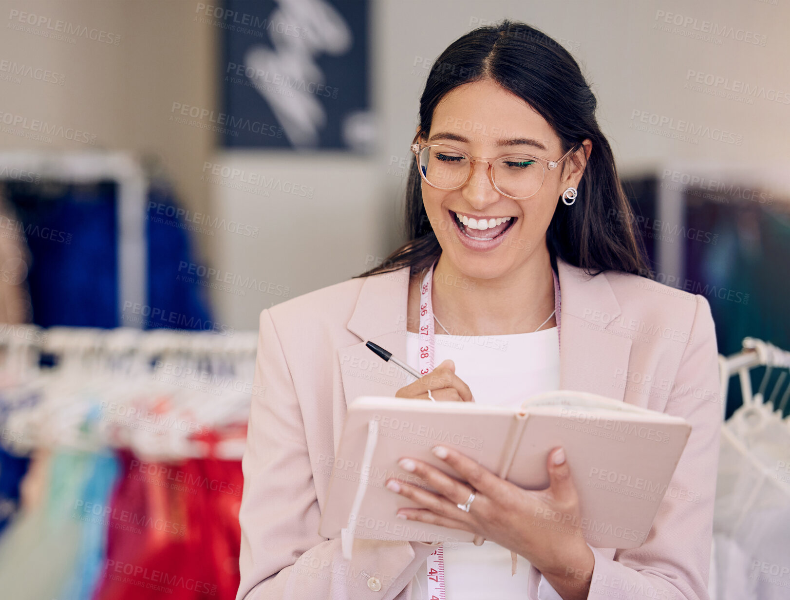 Buy stock photo Shot of an attractive young seamstress writing notes while working in her boutique