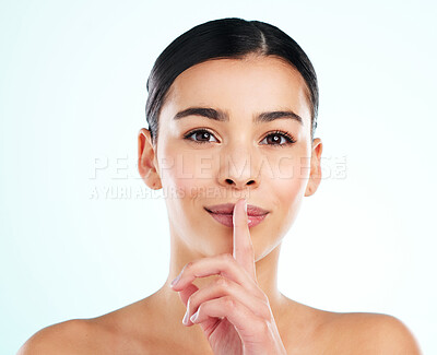 Buy stock photo Beauty, hush and portrait of woman in studio on blue background for cosmetics or dermatology. Face, secret or skincare and confident model with finger on lips for collagen, health or wellness mystery