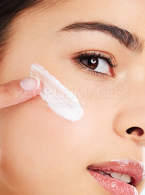 Buy stock photo Studio portrait of an attractive young woman applying face moisturizer against a light background