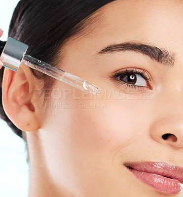 Buy stock photo Studio portrait of an attractive young woman applying antiaging serum to her face against a light background