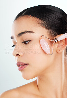Buy stock photo Studio shot of an attractive young woman using a face massager against a light background