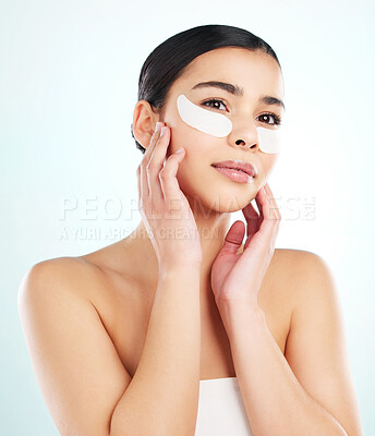 Buy stock photo Studio shot of an attractive young woman using under eye patches against a light background