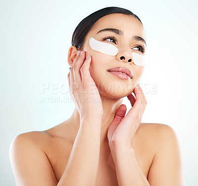 Buy stock photo Studio shot of an attractive young woman using under eye patches against a light background