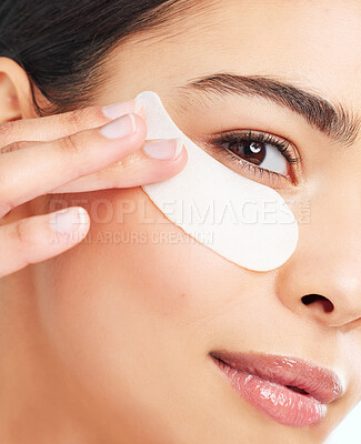 Buy stock photo Studio portrait of an attractive young woman using under eye patches against a light background