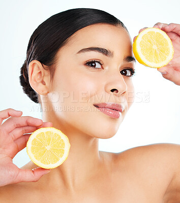Buy stock photo Studio portrait of an attractive young woman posing with a lemon against a light background