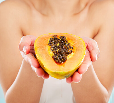 Buy stock photo Studio shot of an unrecognizable young woman posing with a papaya against a light background