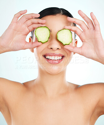 Buy stock photo Studio shot of an attractive young woman posing with cucumber slices against a light background