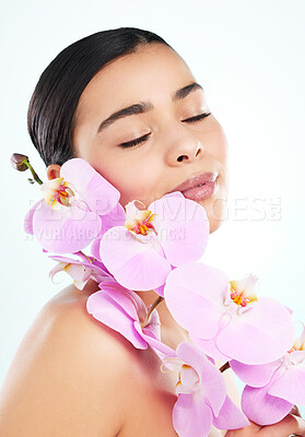 Buy stock photo Studio shot of an attractive young woman posing with a pink orchid against a light background