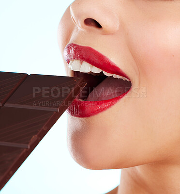 Buy stock photo Studio shot of an unrecognizable young woman biting into a slab of chocolate against a light background