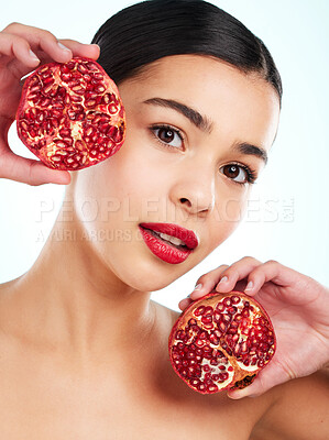 Buy stock photo Studio portrait of an attractive young woman posing with a pomegranate against a light background