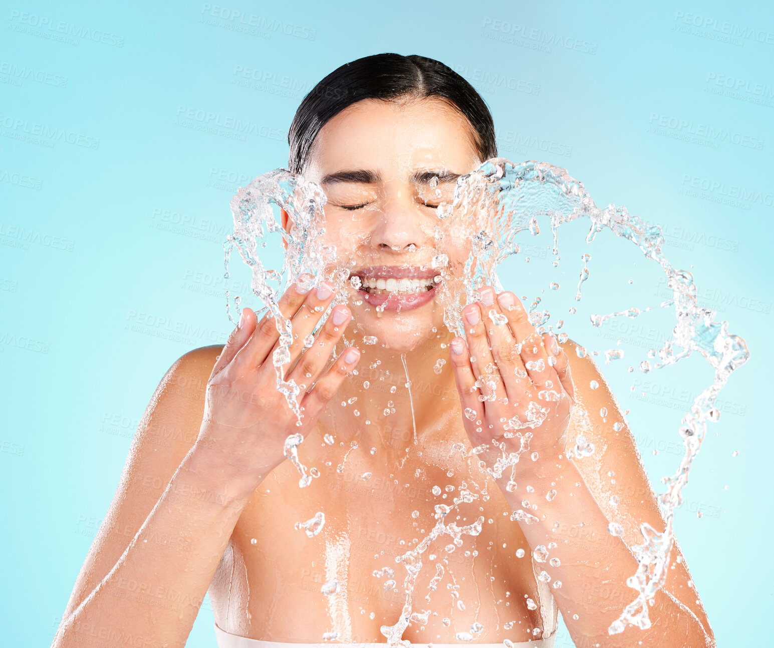 Buy stock photo Shot of a beautiful young woman being splashed with water in the face against a blue background