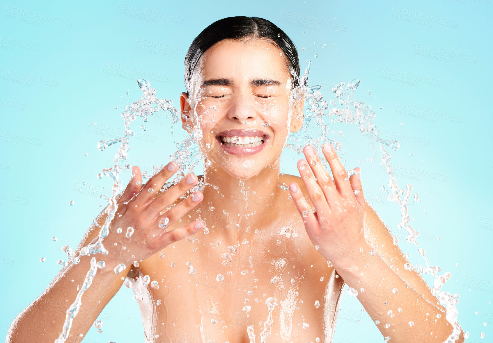 Buy stock photo Shot of a beautiful young woman being splashed with water in the face against a blue background