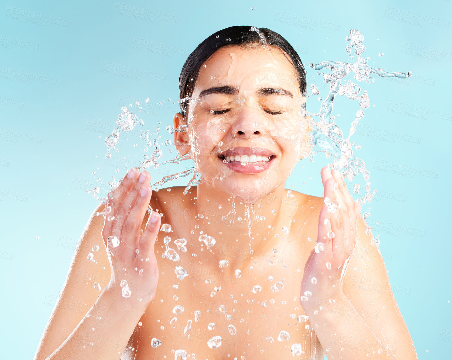 Buy stock photo Hands, woman or water drops in studio for skincare, dermatology and glow or wellness. Hygiene, model girl and smile or happy and liquid or splash for facial and aesthetic or shine by blue background 