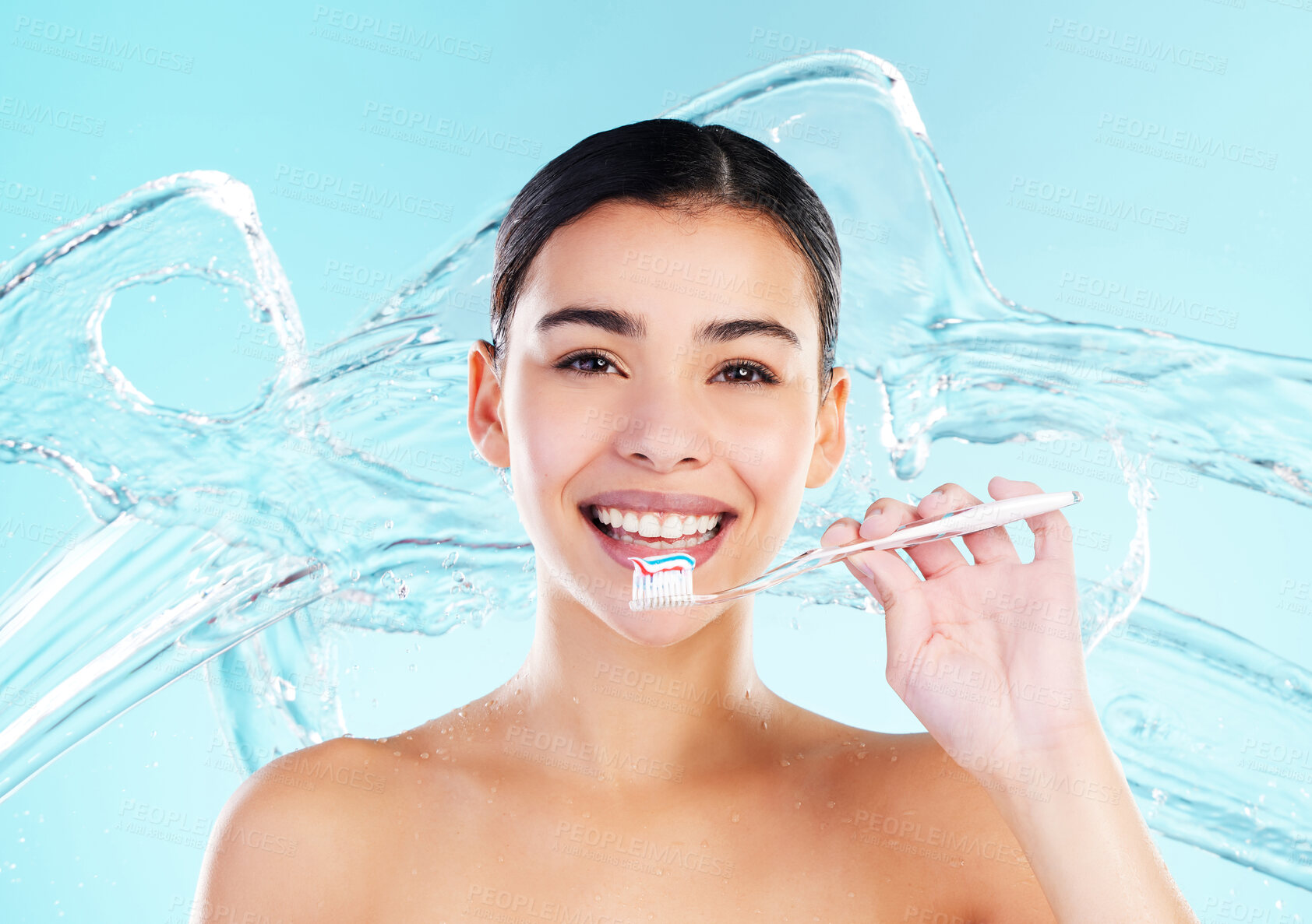 Buy stock photo Girl, water splash and brushing teeth in studio portrait with smile, wellness or cleaning by blue background. Woman, model and toothbrush for routine, oral health or cosmetics with results for beauty